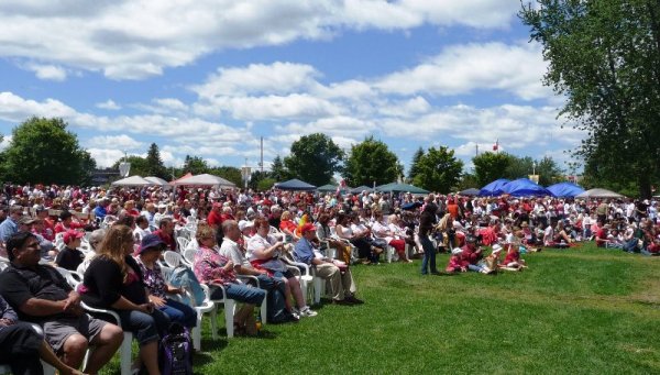 hundreds of people sitting in lawn chairs in Del Crary Park as part of Canada Day celebrations