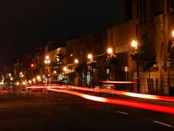 Downtown Peterborough at night, with blurred red tail lights of moving cars