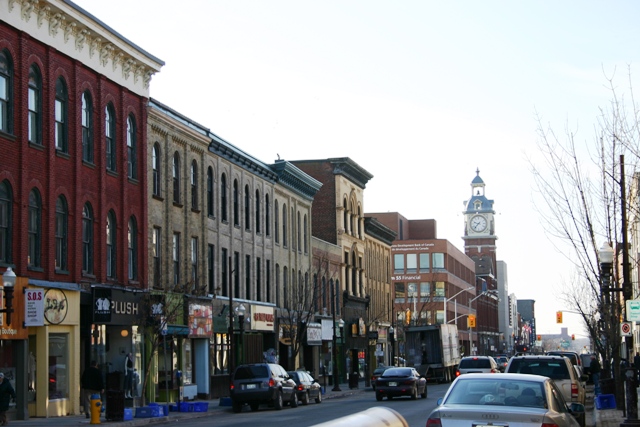 George Street in downtown with several local businesses, apartments, and cars, with the Market Hall clock tower in the background