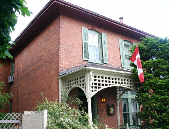 Front of an older two-storey red brick house with a Canada flag