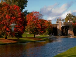 Trent Canal edged by trees with bright red leaves and Peterborough Lift Lock in the background