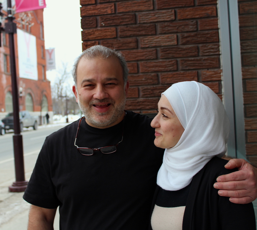 Mohammad Alftih with his arm around his wife, Randa Kharboutly's, shoulder. Both are smiling in front of the Syrian restaurant they opened, which is called OMG