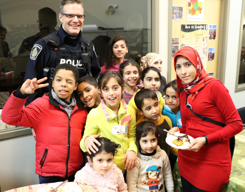 Peterborough police officer with 12 kids and an adult, all smiling in a local restaurant