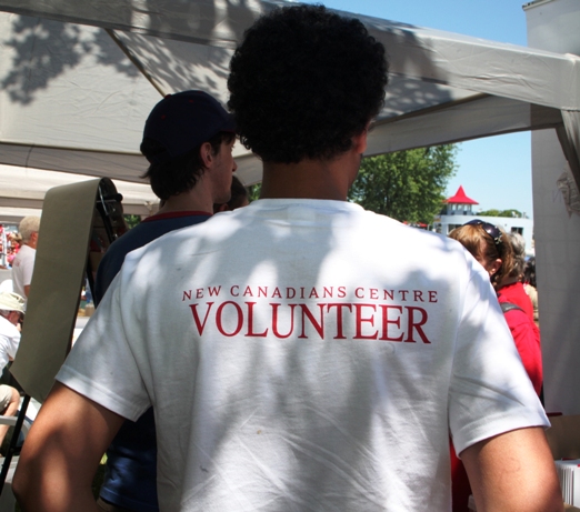 Man wearing white tee shirt with New Canadians Centre Volunteer written on its back